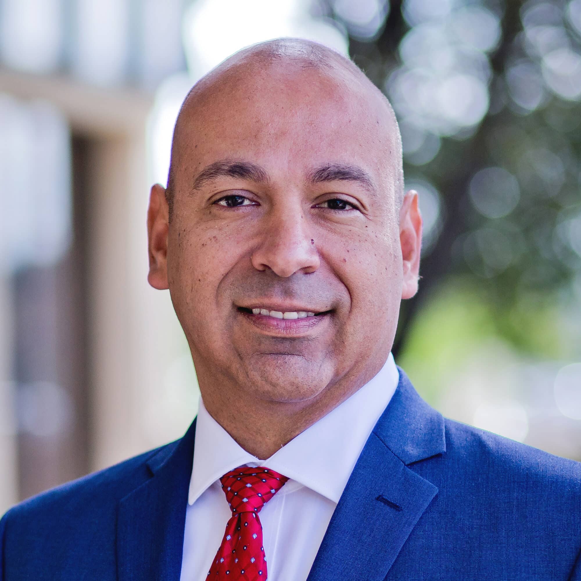 Professional man in suit with red tie smiling.