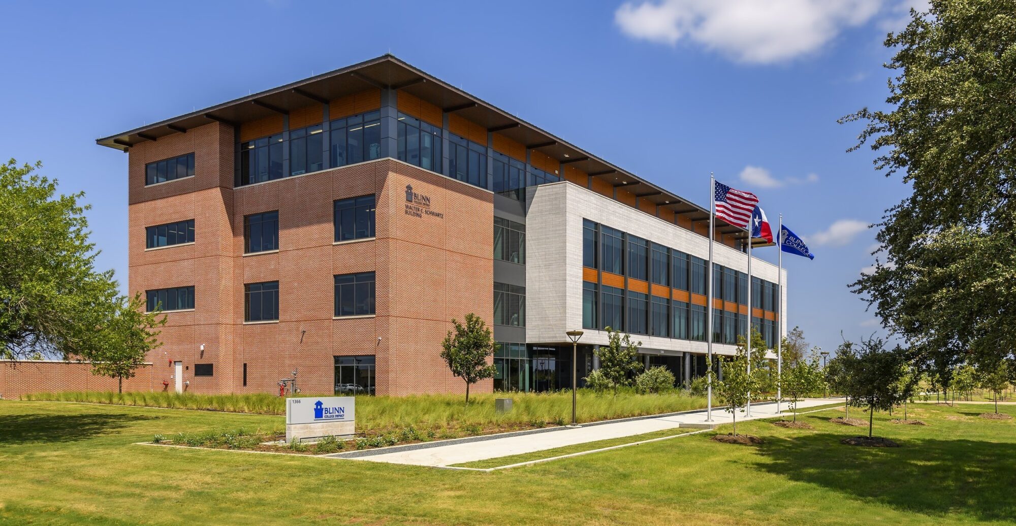 Modern educational building with US and Texas flags.