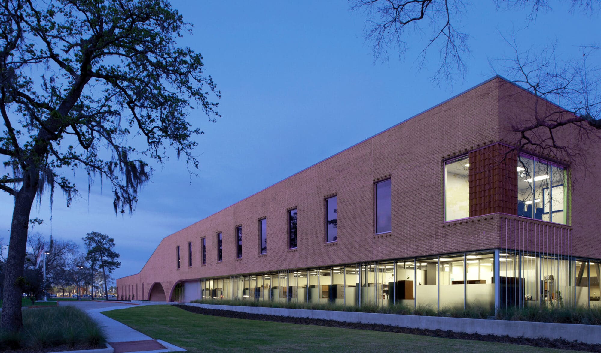 Modern brick building at dusk with illuminated windows