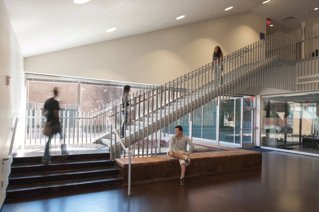 Modern lobby with staircase and people.