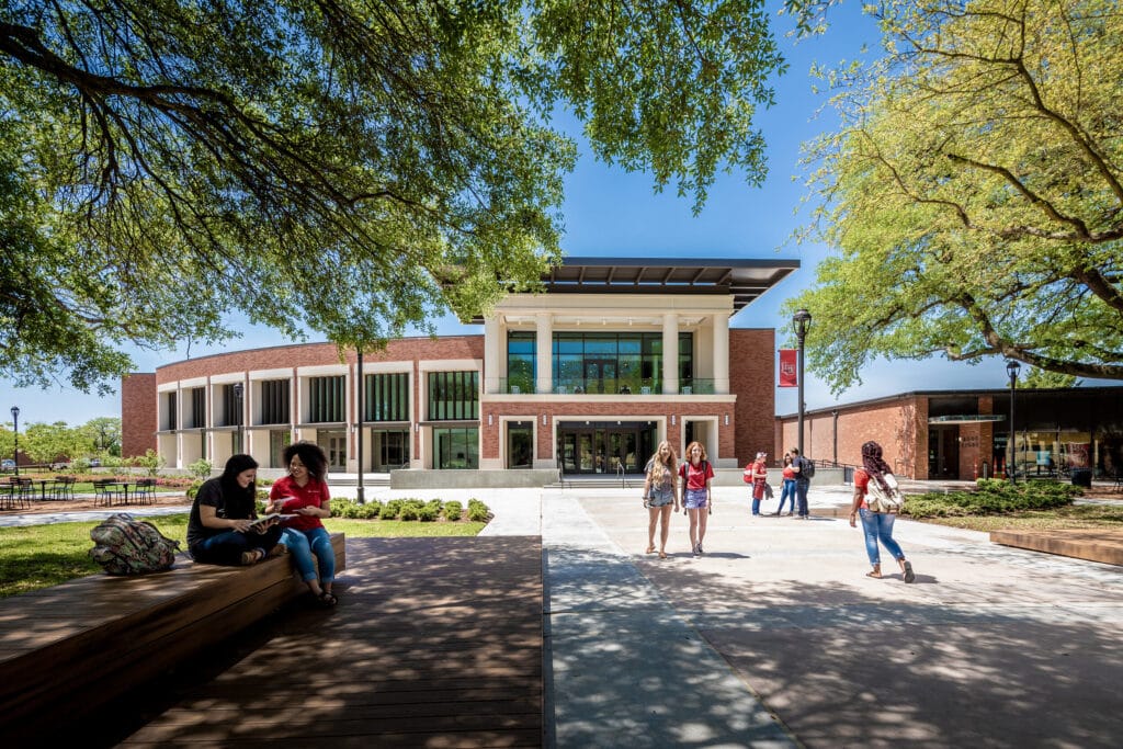 Students outside modern university campus building.