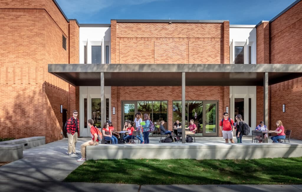 Students socializing outside modern brick campus building.