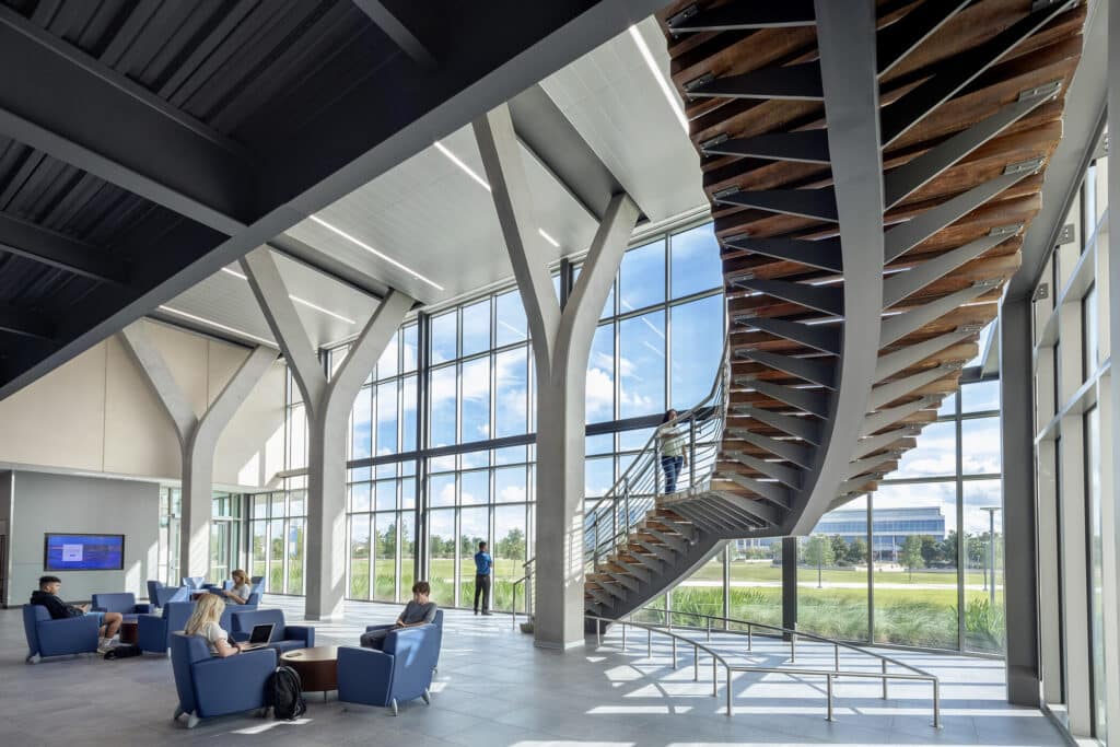 Modern lobby with wooden staircase and seated people.