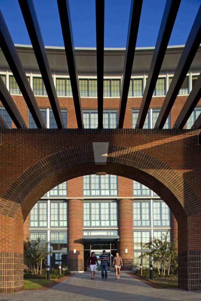 Modern brick building with archway and pedestrians.