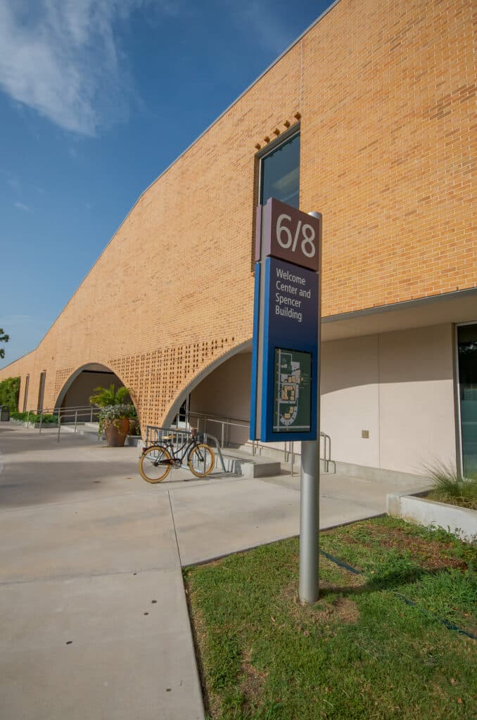 Modern building with arched entrance and signpost.