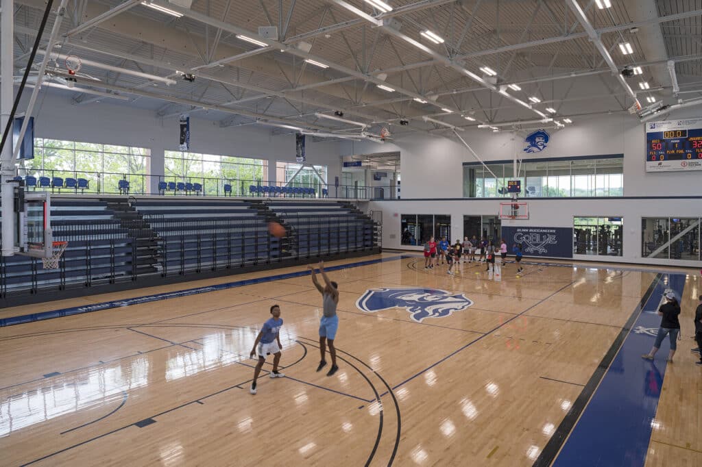 Indoor basketball court with players shooting hoops.