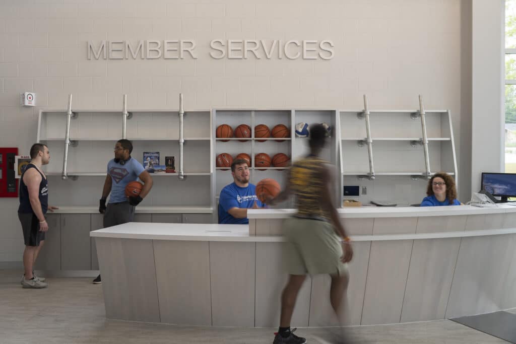 People at gym member services desk with basketballs.