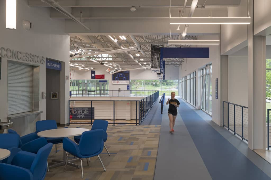 Indoor track with running person and seating area.