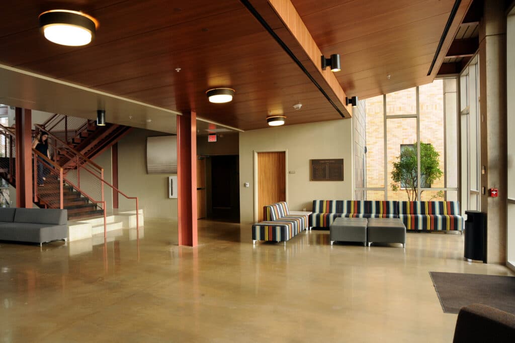 Modern lobby interior with staircase and colorful furniture.