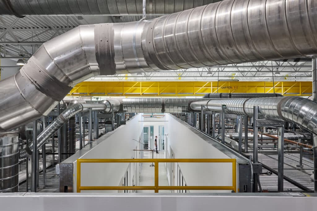 Industrial facility with large overhead ductwork and walkway.