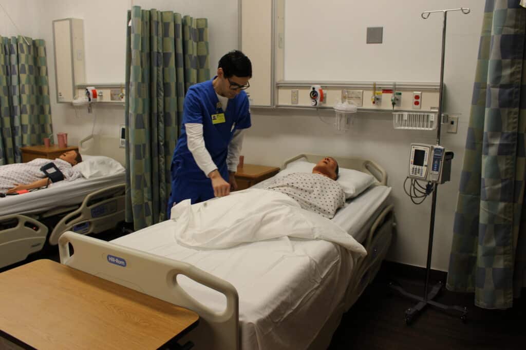 Healthcare professional attending to patient in hospital room.