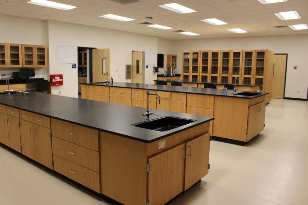 Modern laboratory interior with wooden cabinets and benches.