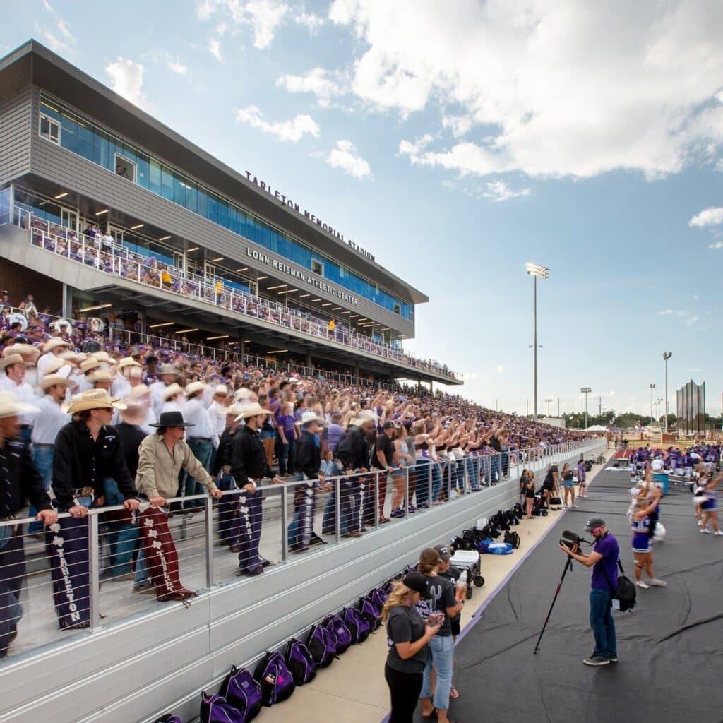 Crowded sports stadium with enthusiastic fans and camera crew.