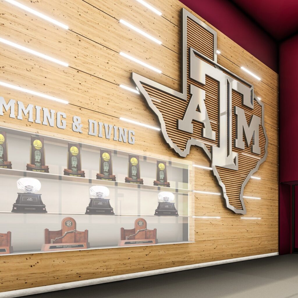 Trophy display with illuminated collegiate logo on wood wall.