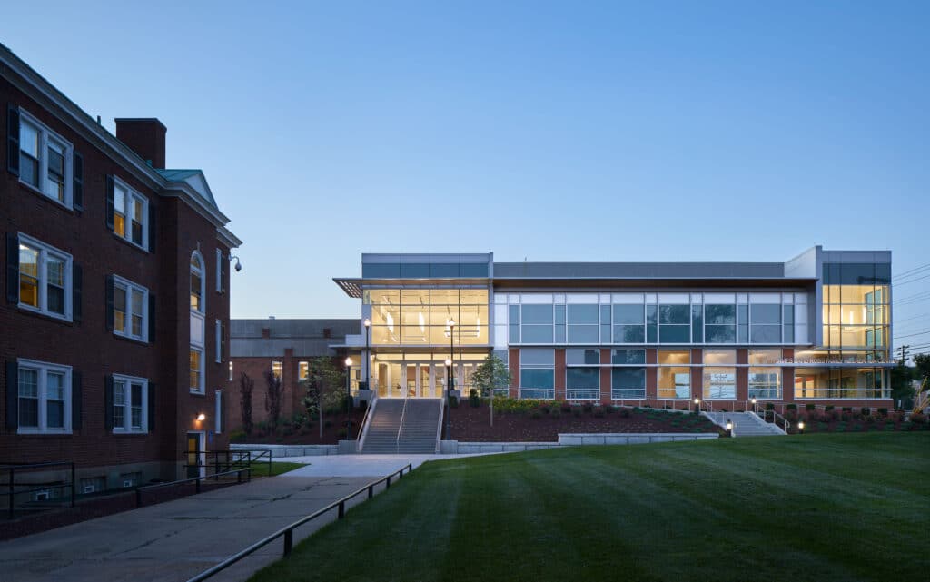 Modern university building at dusk with lights.