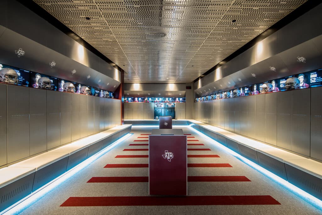 Modern football locker room with LED lighting and monitors.