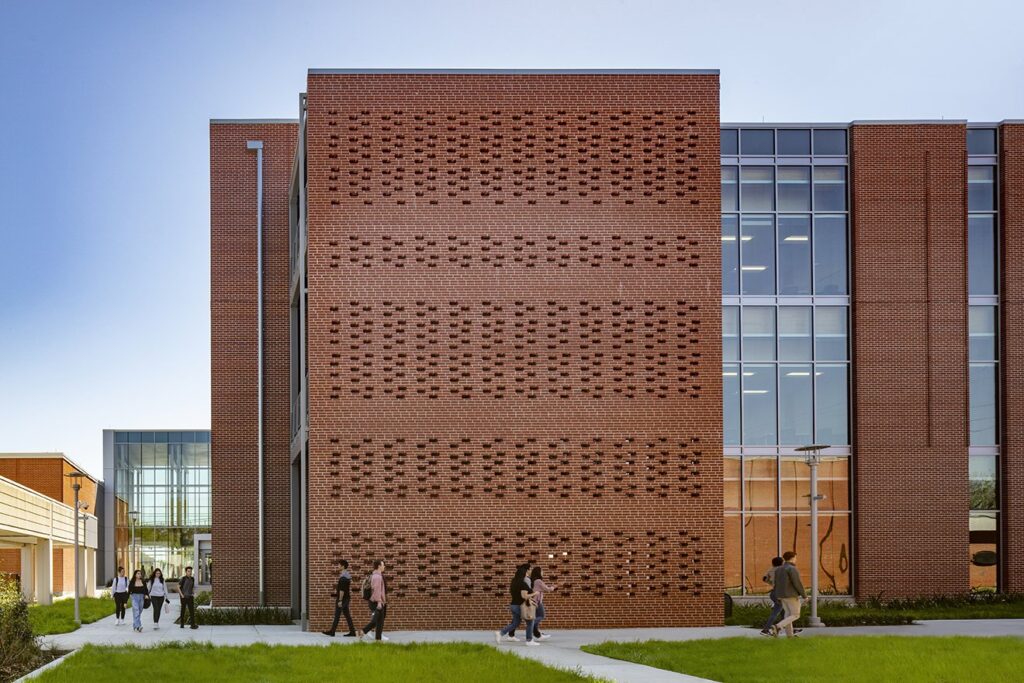 Students walking by modern brick building campus