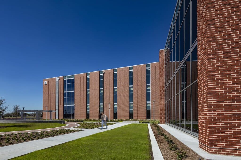 Modern brick building with glass facade and pedestrian.