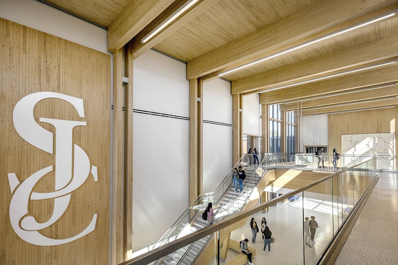 Modern interior with wood design, staircases, and people walking.