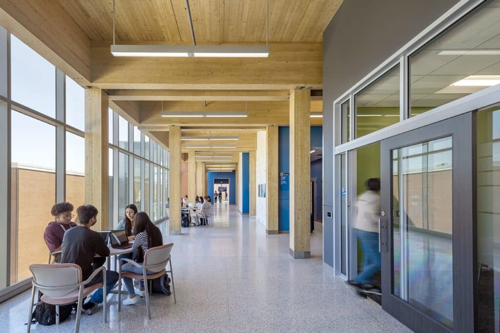 Students studying in sunlit modern corridor