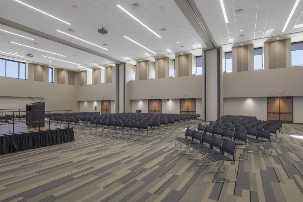 Spacious modern auditorium with rows of chairs and podium.