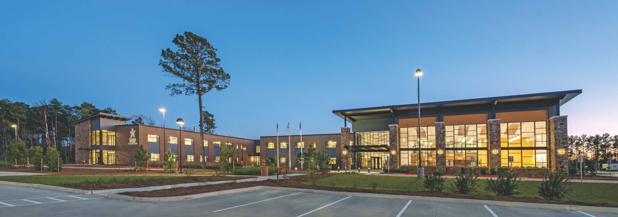 Modern school building at dusk with lights on.