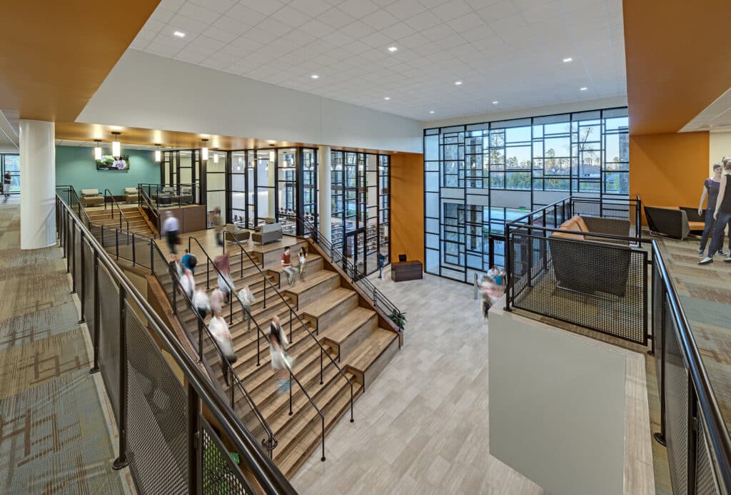 Modern office lobby with stairs and people.