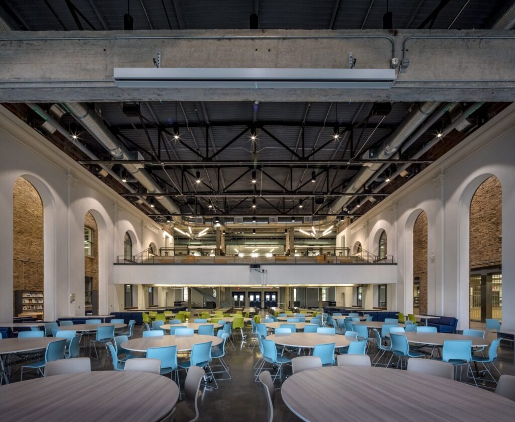 Modern industrial cafeteria interior with colorful chairs.