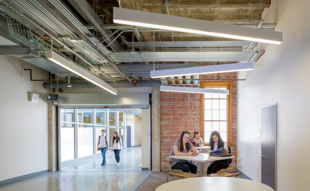 Modern office space with exposed ceiling and people.