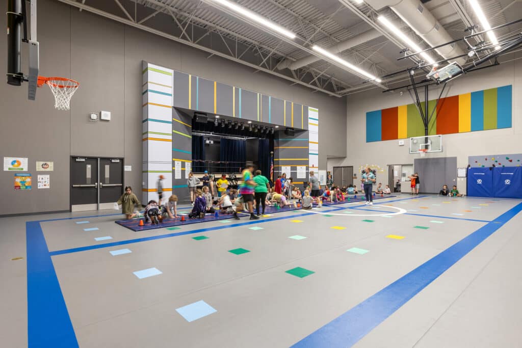 Children playing in colorful school gymnasium.