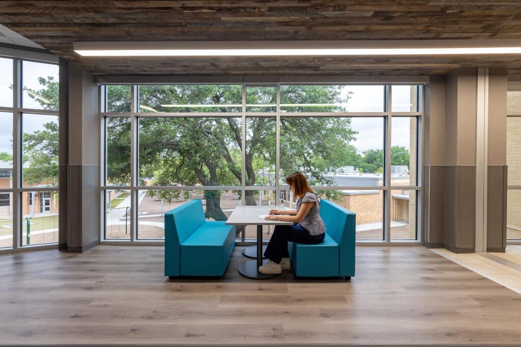 Woman sitting at table in modern office lounge.