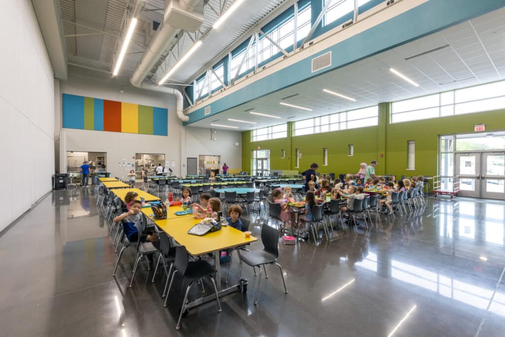 Children eating lunch in a bright school cafeteria.