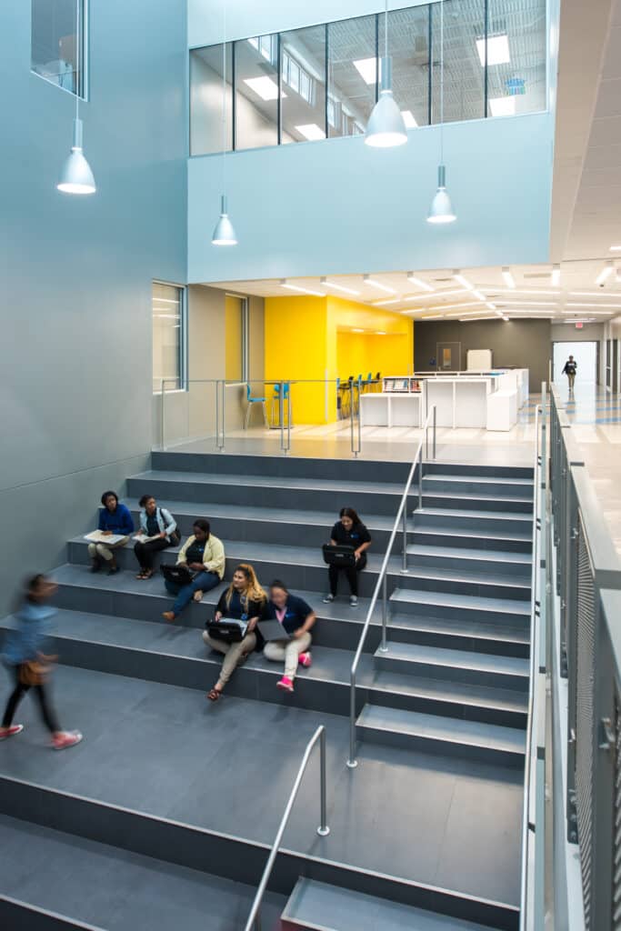Modern school atrium with students and staircase.