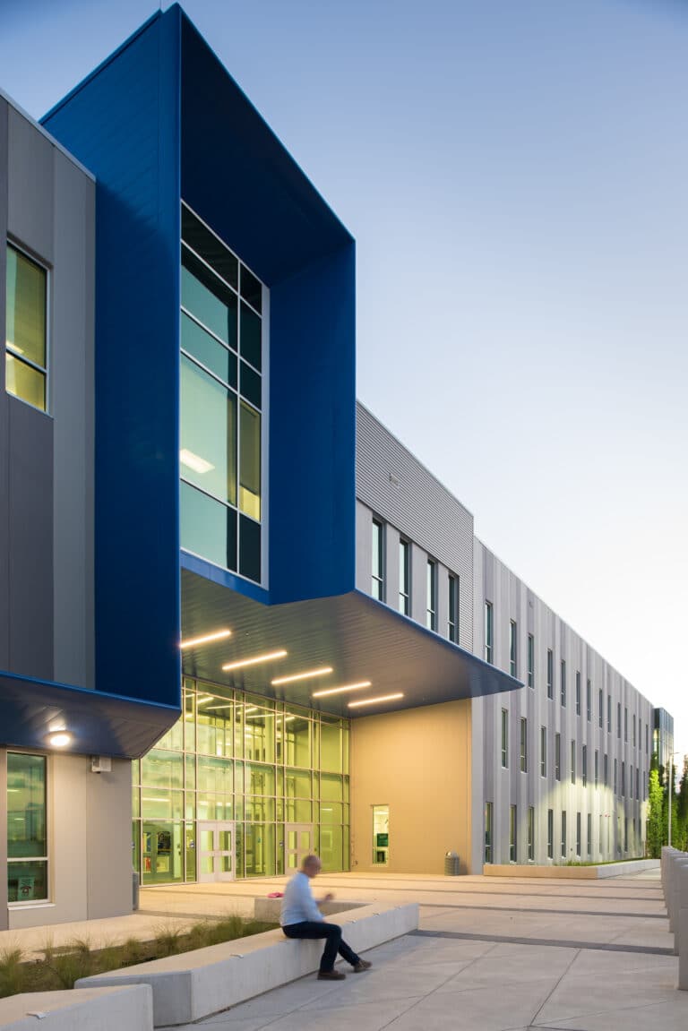 Modern building exterior at twilight with person seated.